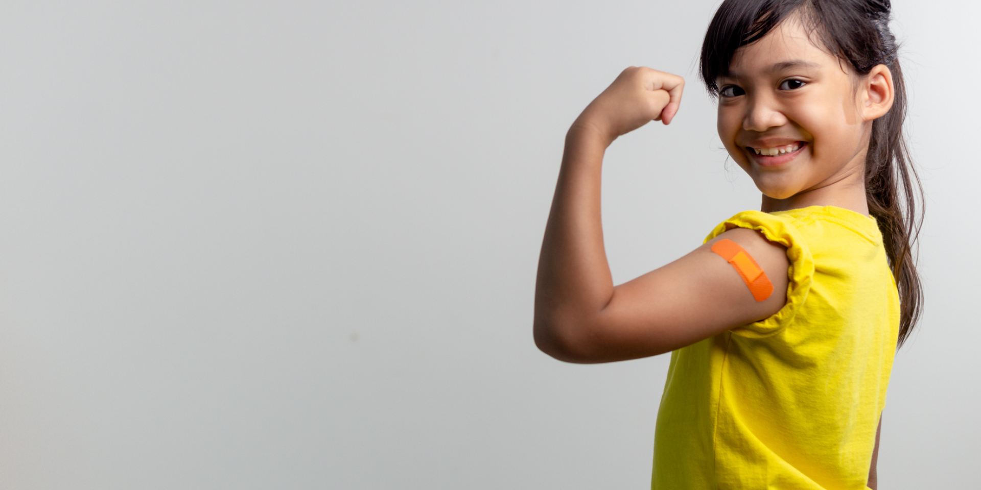 School-age girl shows off her Band Aid®, after getting her back-to-school immunizations.