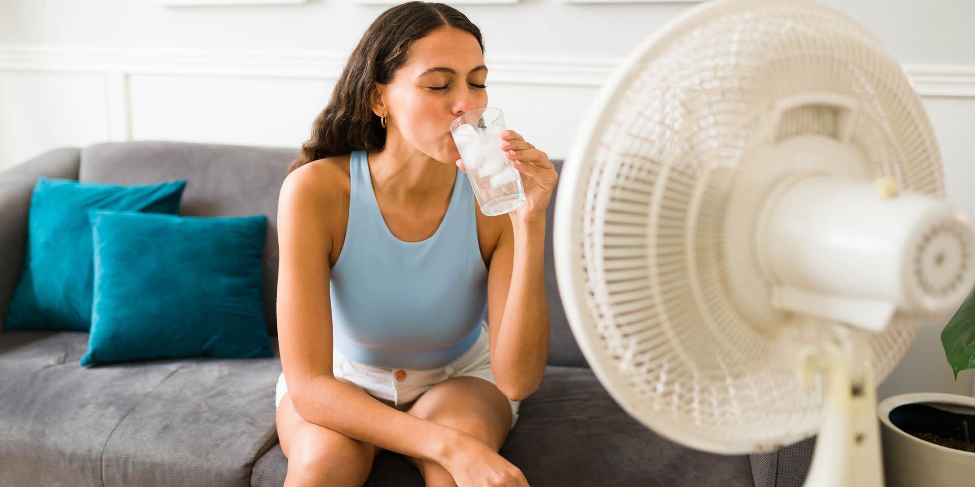 Woman sitting in front of a fan drinking water. | Doylestown Health