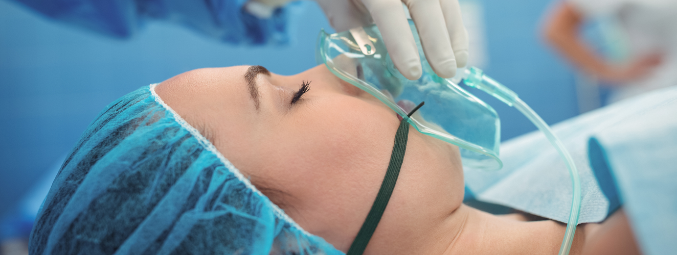 Surgeon adjusting oxygen mask on patient mouth in operation theater at hospital | Doylestown Health