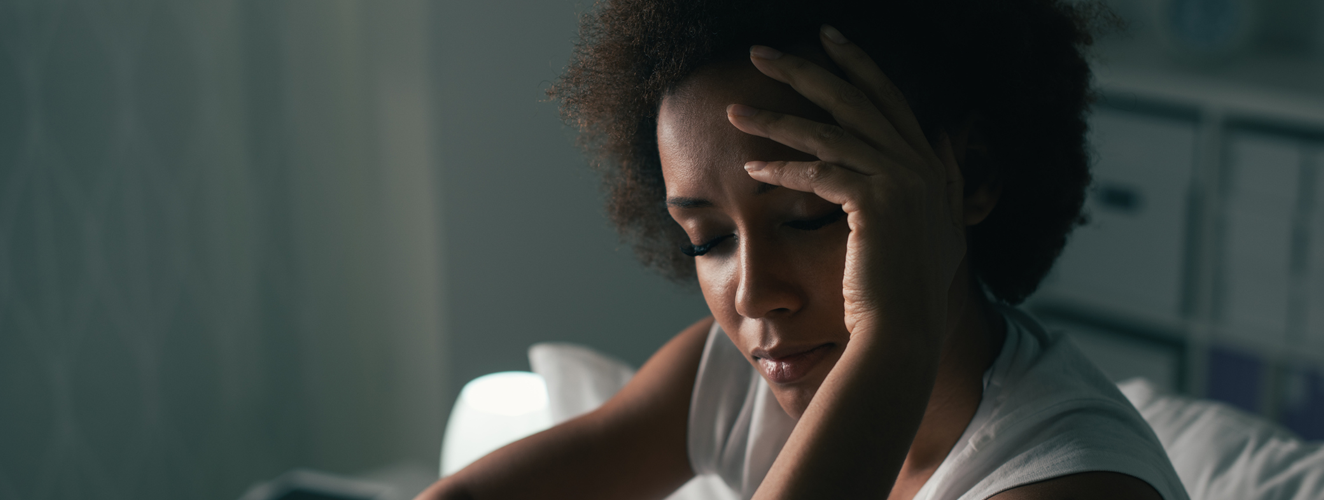 Woman suffering from insomnia, she is sitting in bed and touching her forehead, sleep disorder and stress | Doylestown Health